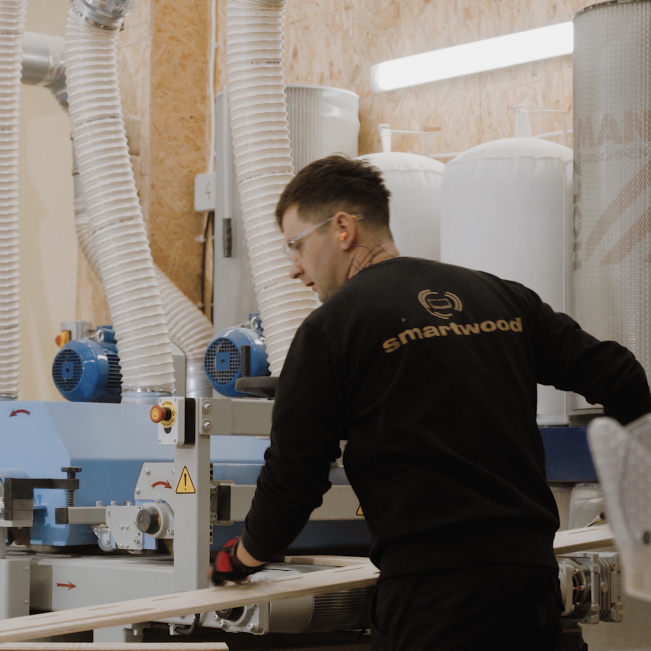 Pracownik używający maszyny do obróbki płyty sosnowej